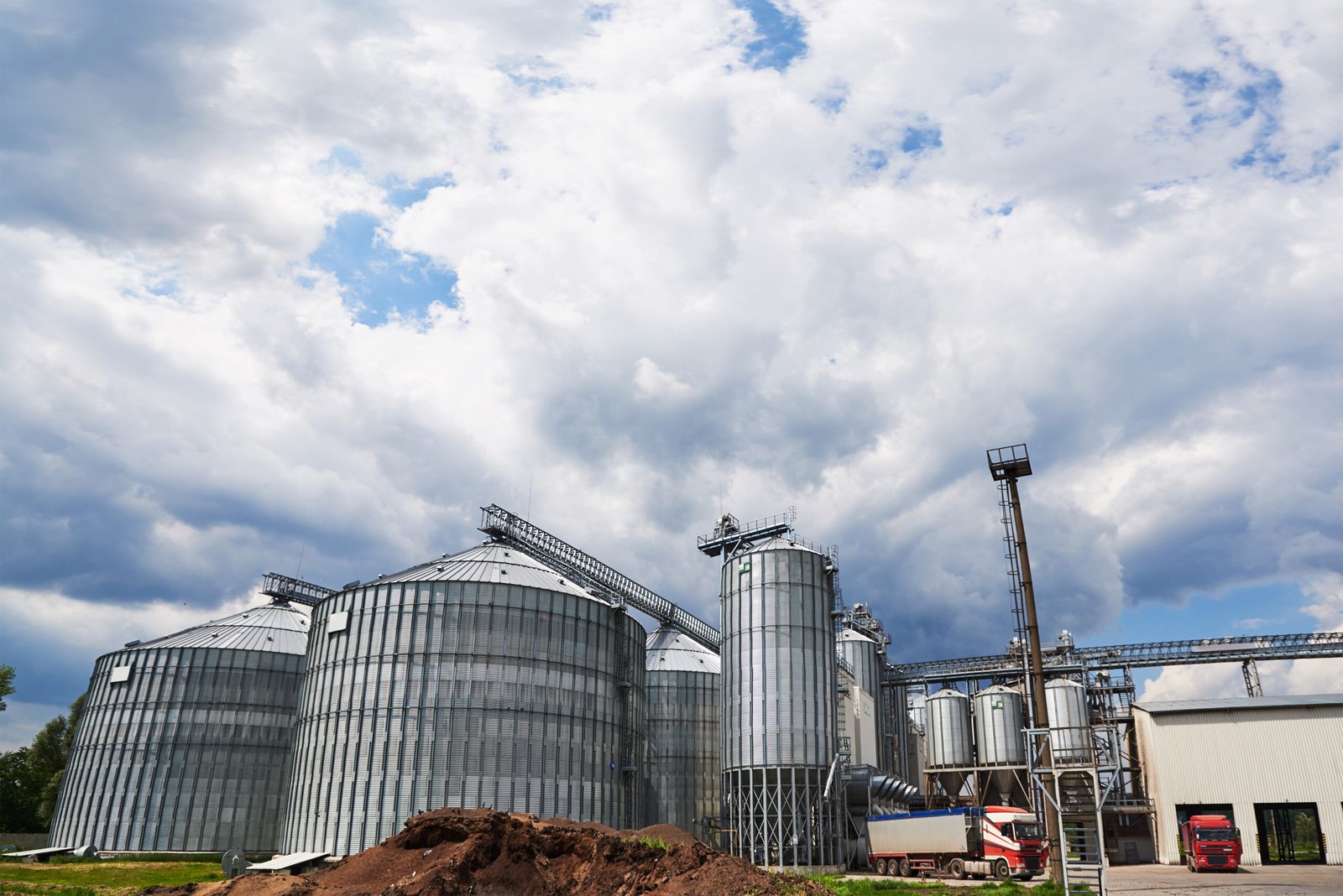 Agricultural Silos. Building Exterior. Storage and drying of grains, wheat, corn, soy, sunflower against the blue sky with white clouds
