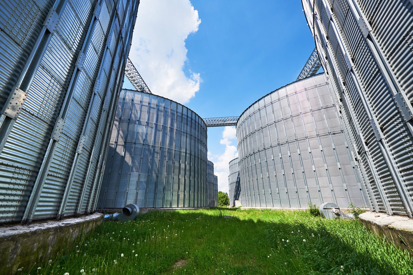 Agricultural Silos. Building Exterior. Storage and drying of grains, wheat, corn, soy, sunflower against the blue sky with white clouds