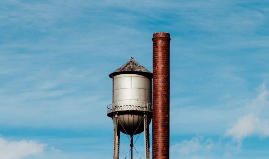 A closeup of a tall water tower with a metal large pipe next to it