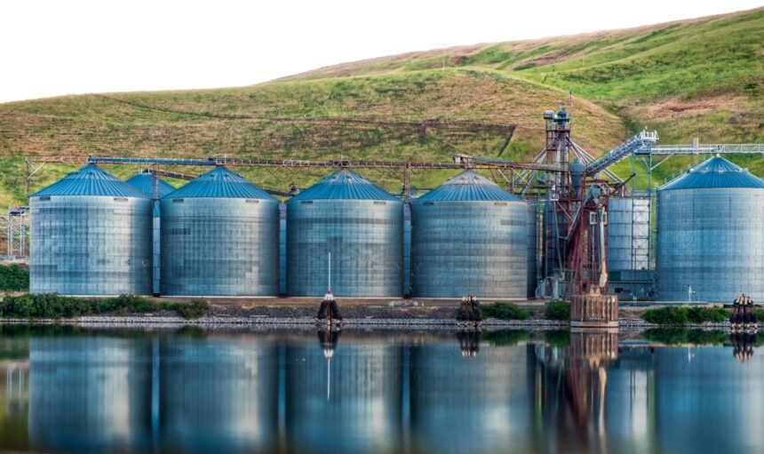 A panoramic shot of industrial buildings on the shore of the lake reflected in the water