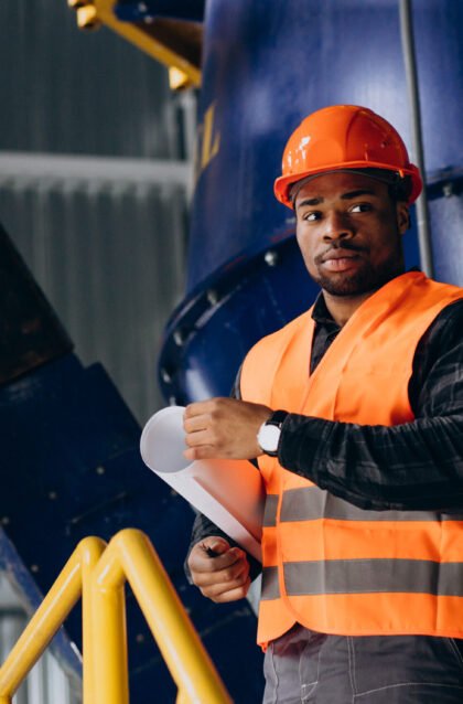 African american worker standing in uniform wearing a safety hat in a factory